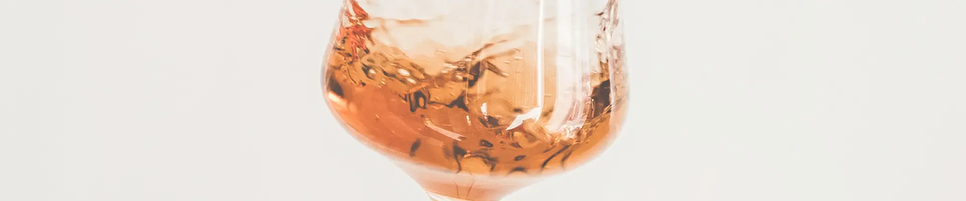 Ein schwingendes Weinglas mit Orange Wein gefüllt.