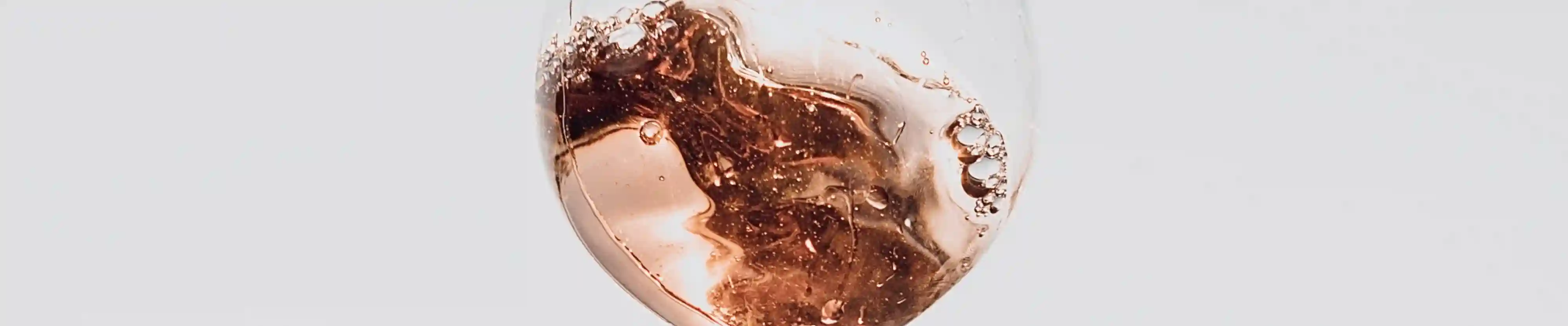 Ein schwingendes Weinglas mit Rosé Wein gefüllt.