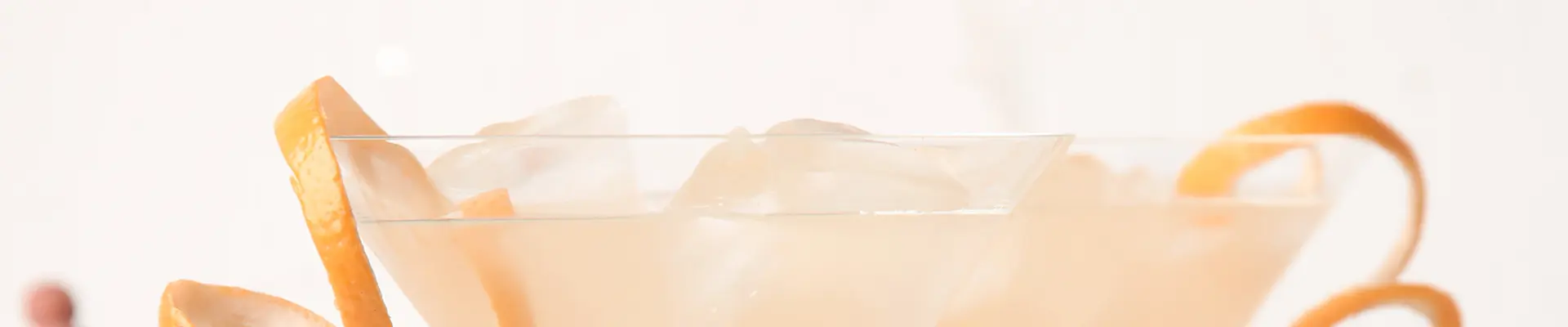 Nahaufnahme eines Drinks mit Orangenschale als Verzierung.