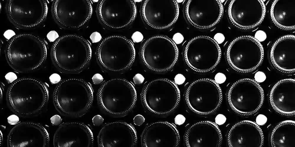 Schwarz-Weiss-Bild von einem Weinregal. Die Flaschen sieht man von unten.